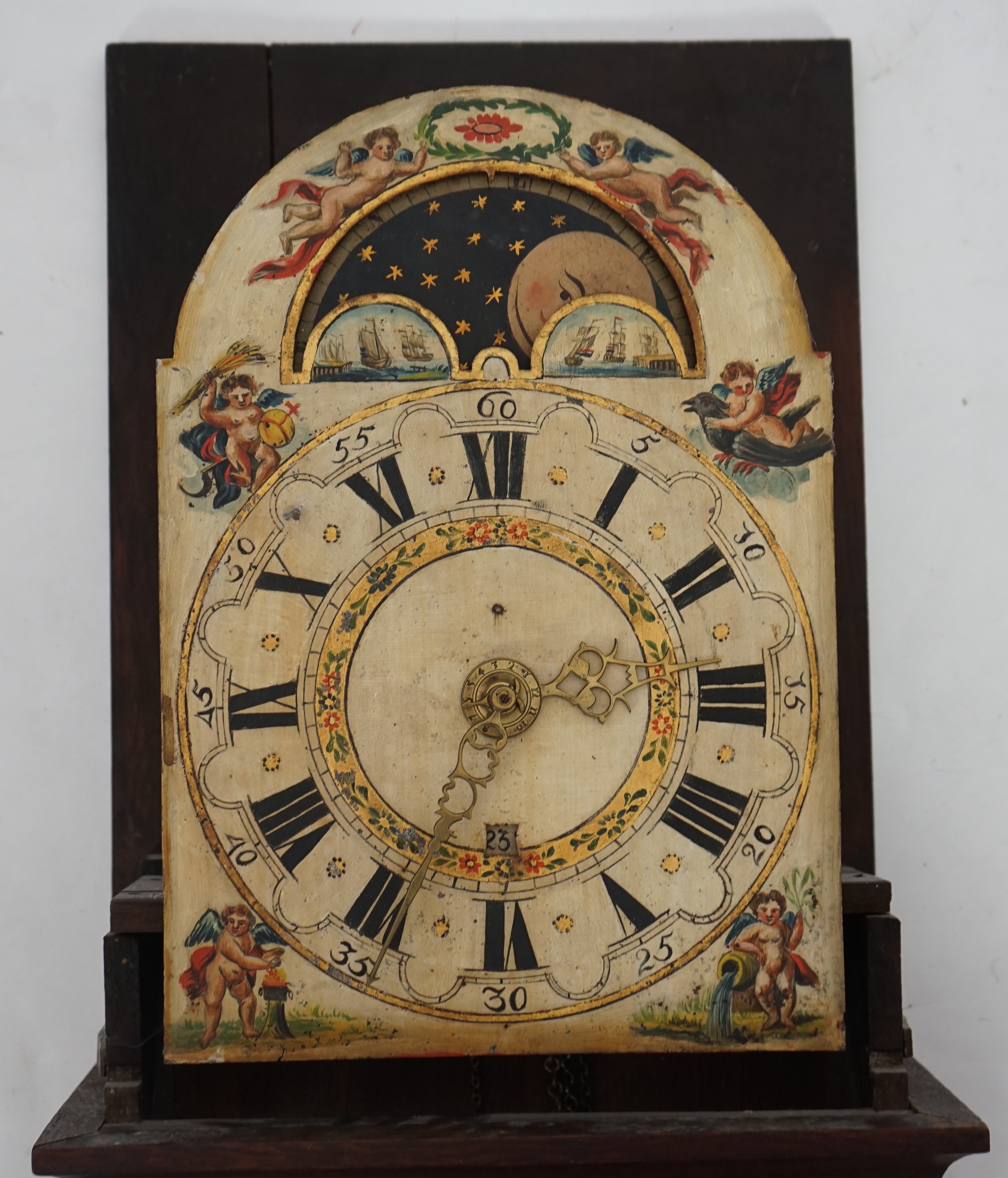 A late 18th century Dutch Frisian Staart oak eight day wall clock, with atlas and angel finials, hood painted with a Dutch riverscape and painted arched dial with moonphase, date aperture and alarm indicator, 47cm wide,